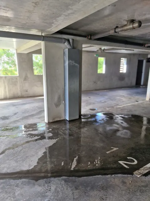 Descente d'eau pluviale dans un parking couvert, flaque au sol