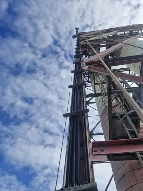 Câbles fixés le long de l'armature métallique de la cheminée de la centrale de Bois-Rouge, vus depuis le bas