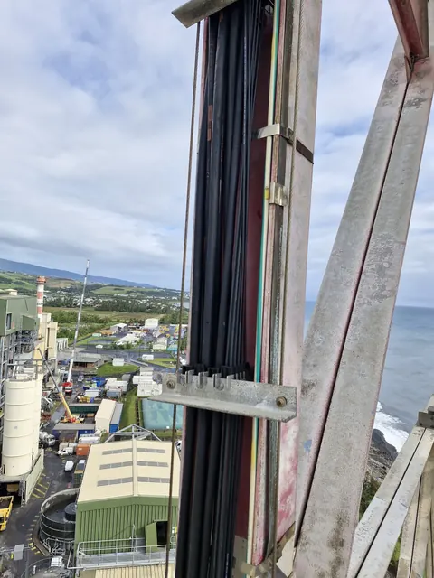 Faisceau de câbles fixé sur une structure métallique, la côte et la mer en arrière-plan