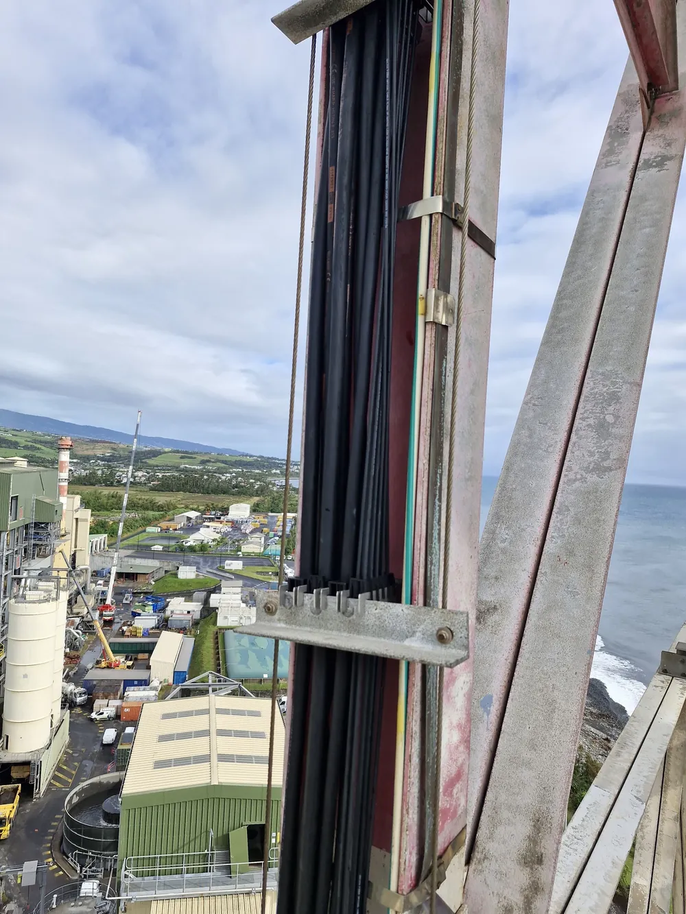 Faisceau de câbles fixé sur une structure métallique, la côte et la mer en arrière-plan